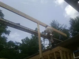 Carpenter setting a ridge beam over a new addition frame — Ice Dam Removal by Roofing Brothers in Conowingo
