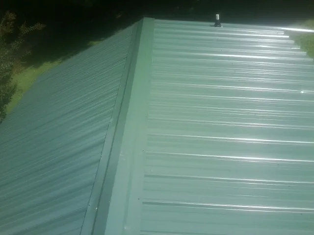 New green metal panels meeting at the ridge of a roof — Flat Roof Repair work by our crew in Conowingo