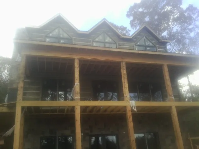 Dormers and porch framing on a large log home under construction — Roof Coating work by our crew in Conowingo