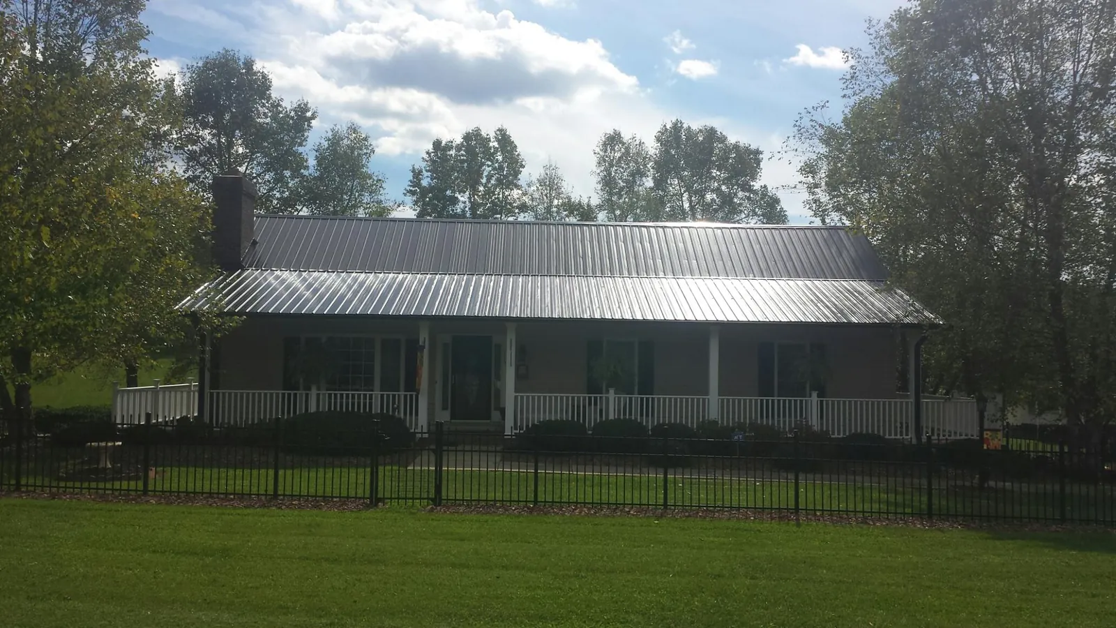 Gray metal roof on a brick ranch with a full width front porch — Gutter Guard Installation work by our crew in Conowingo