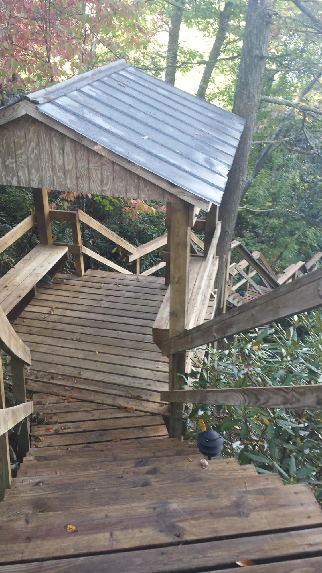 Metal roofed shelter over wooden steps on a wooded walkway — Skylight Repair & Installation work by our crew in Conowingo