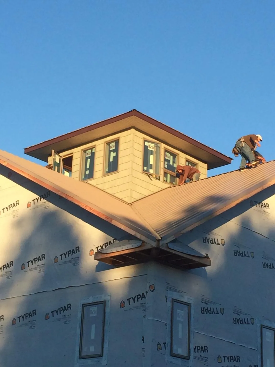Roofers working around a rooftop cupola on a new metal roof at sunset — Roof Waterproofing in Conowingo by Roofing Brothers